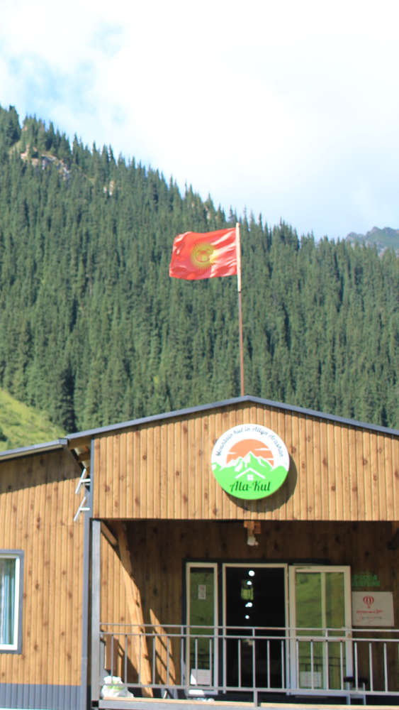 Photo of the main building of the guesthouse, with the flag of Kyrgyzstan flying over the roof